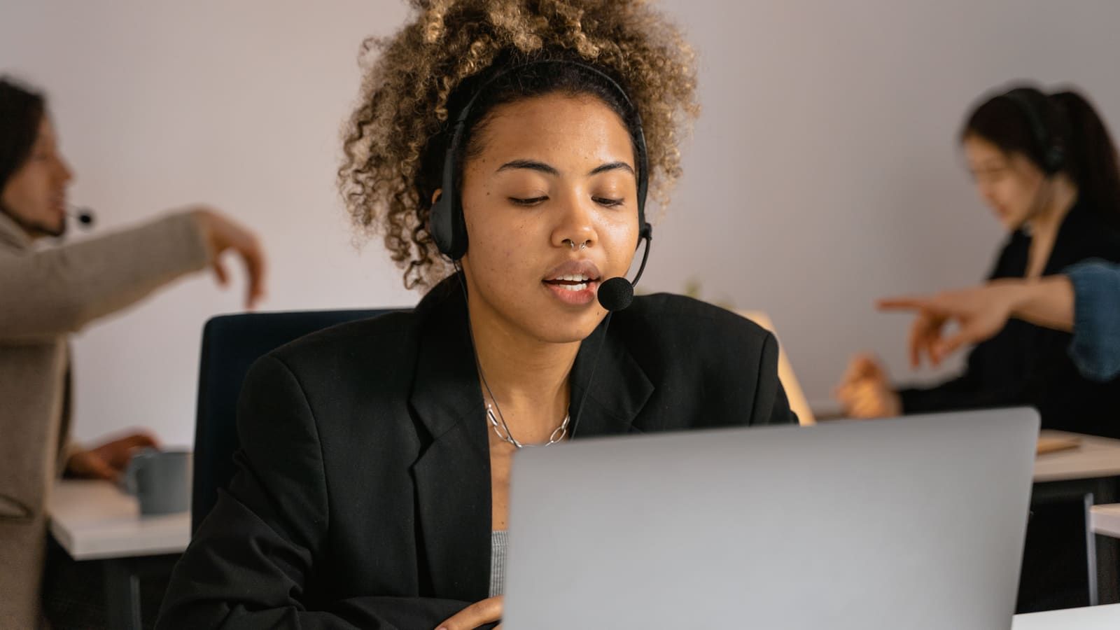 Customer support agent with headset working on laptop in office