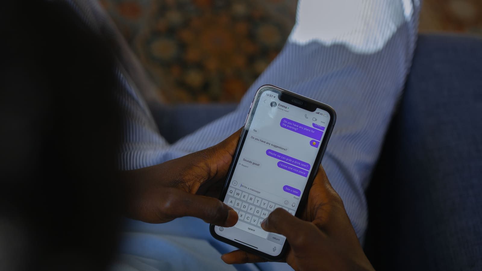Close-up of hands holding a smartphone, typing a message on a touch screen indoors