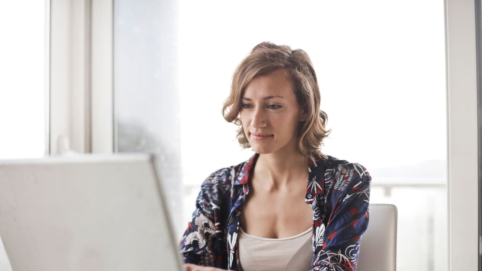 A woman typing on a laptop in a bright, modern home office setting