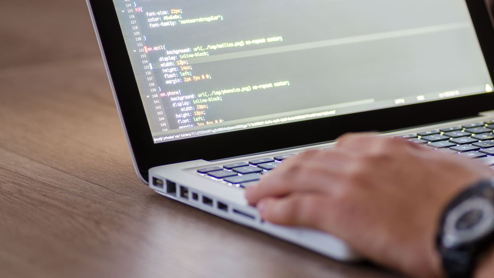 Person coding on a laptop with HTML code on screen, showcasing development work
