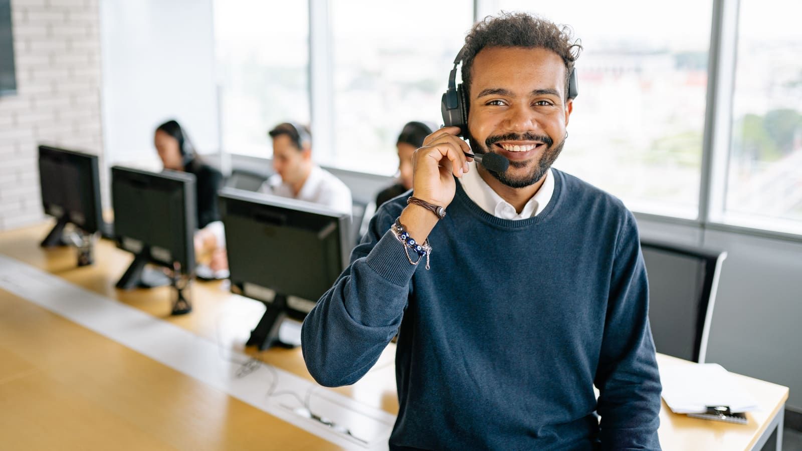 Cheerful male call center agent with headset in a bright office environment