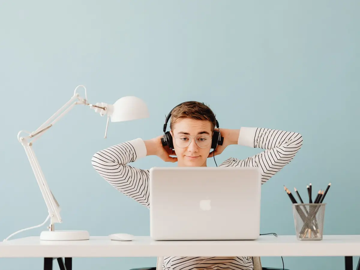 A relaxed founder leaning back from the laptop while the AI agent handles support